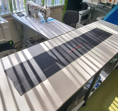 Industriële naaimachine met een baan gestreepte stof in het atelier Industriële naaimachine met een baan gestreepte stof in het atelier